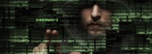 Hooded man hacking into a computer.
