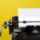 Close-up a black typewriter with a yellow background.